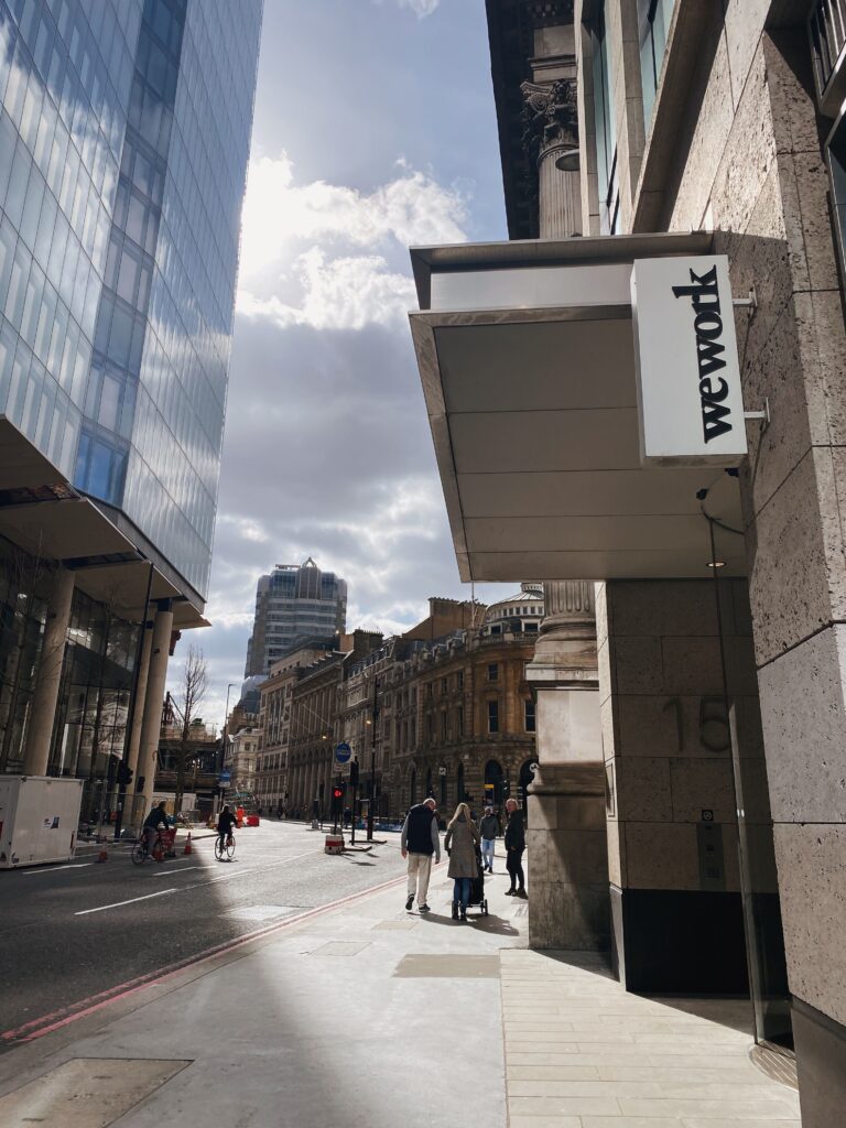 A bustling street in Greater London featuring modern architecture and a WeWork sign. Daytime city scene.